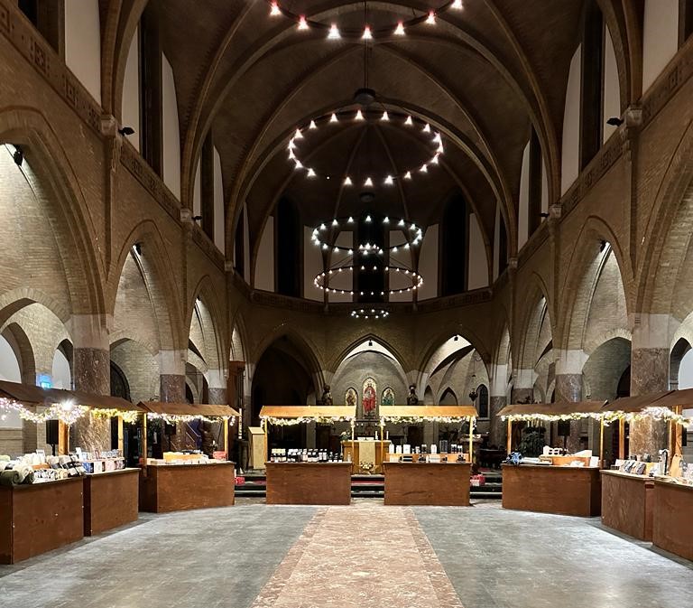 Geschenkenmarkt in een sfeervolle kerk met kramen en kroonluchters